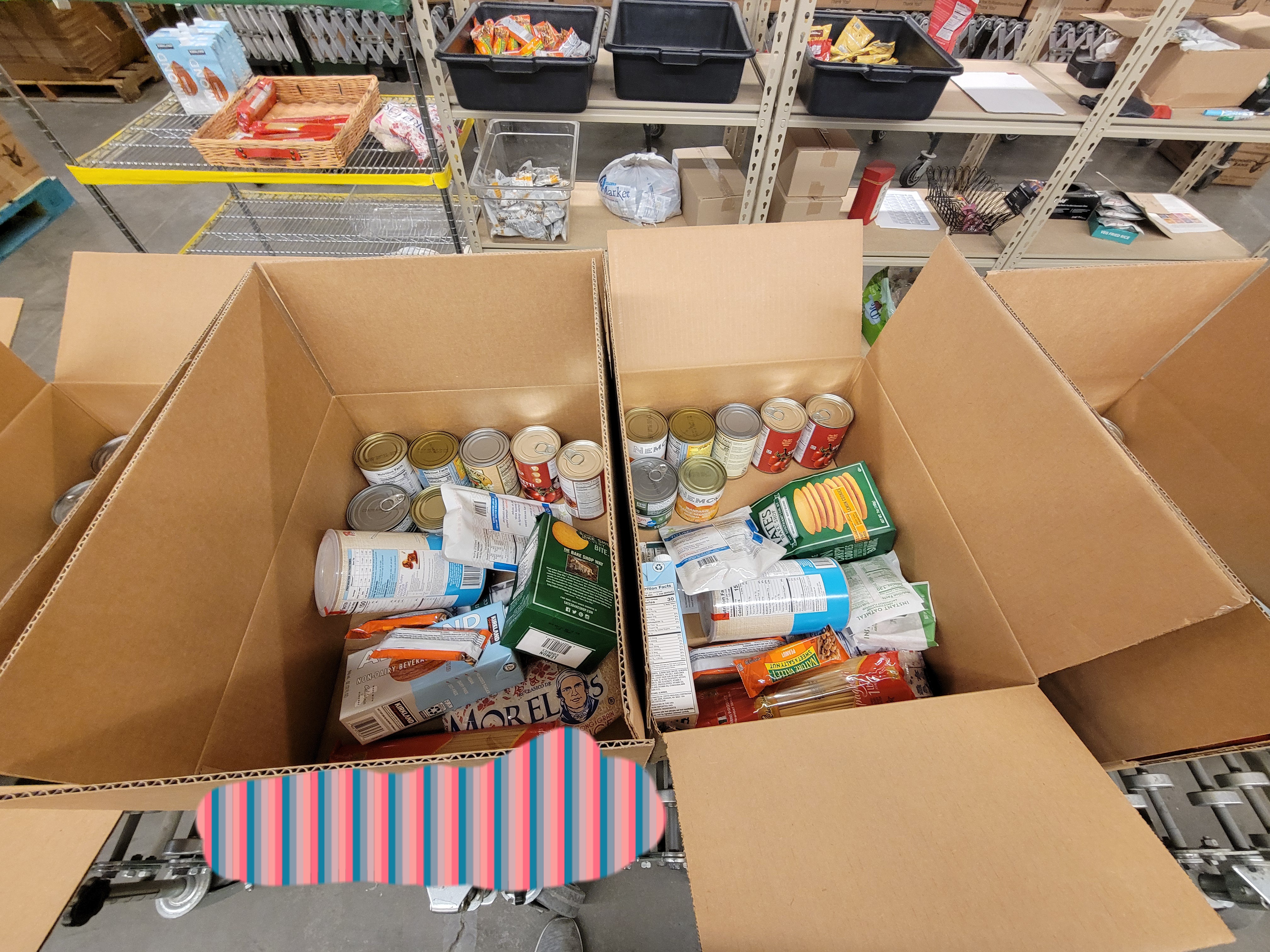 Cardboard boxes of dry goods with a shelf behind it.